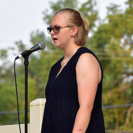 a woman singing into a microphone outside.