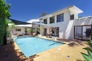 Rectangular Swimming Pool In Back Of A Large White House