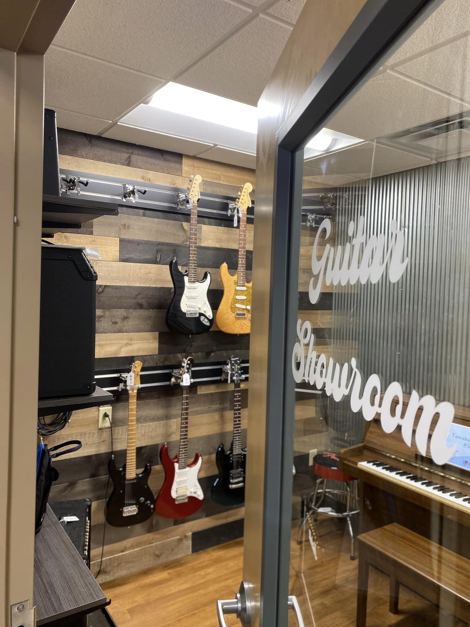 A guitar showroom. Guitars hang on shelves and sit next to amplifiers.